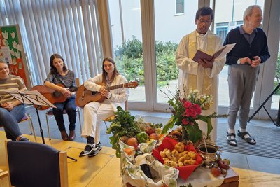 Pater Nelson, Gitarrenspielerinnen und Bewohner beim Erntedankfest