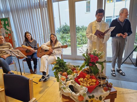 Pater Nelson, Gitarrenspielerinnen und Bewohner beim Erntedankfest