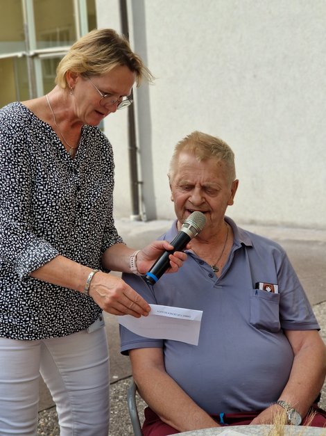 Bewohner liest Text, Mitarbeiterin hält Mikrophon